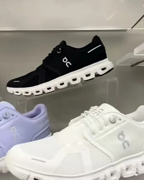 Zapatillas en negro, blanco y lila exhibidas sobre repisas de acrílico